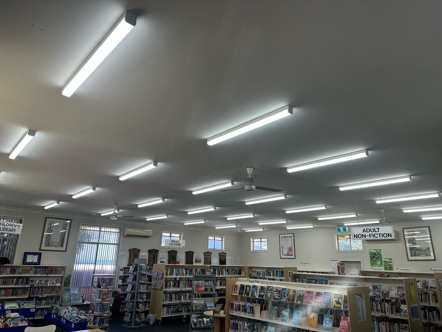 A library with a lot of books on shelves and a lot of lights on the ceiling.