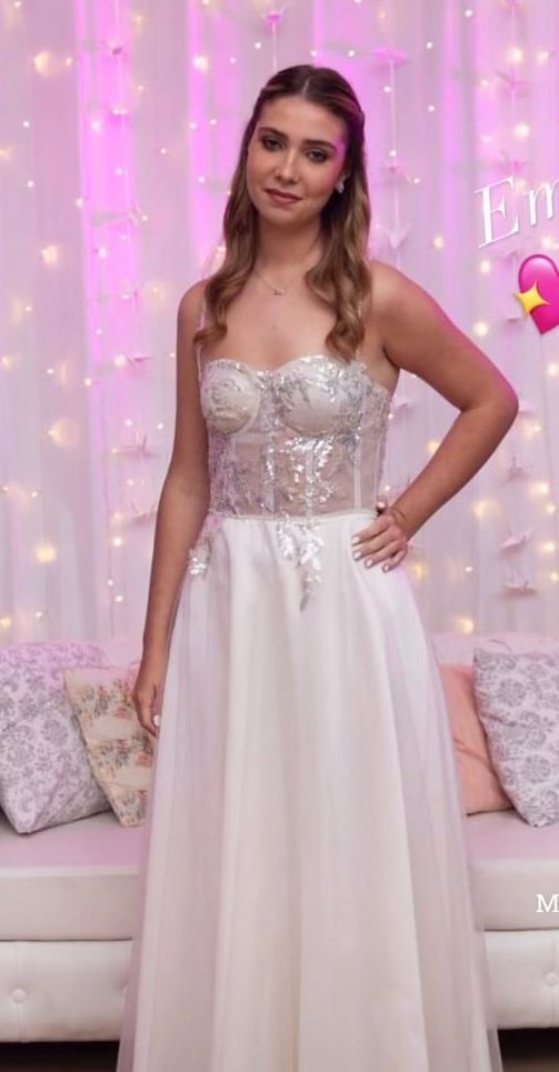 Una mujer con un vestido blanco está parada frente a un sofá.