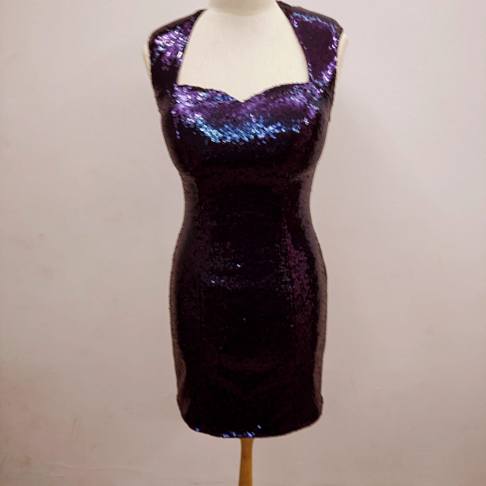 Un vestido morado con lentejuelas está sobre un maniquí.
