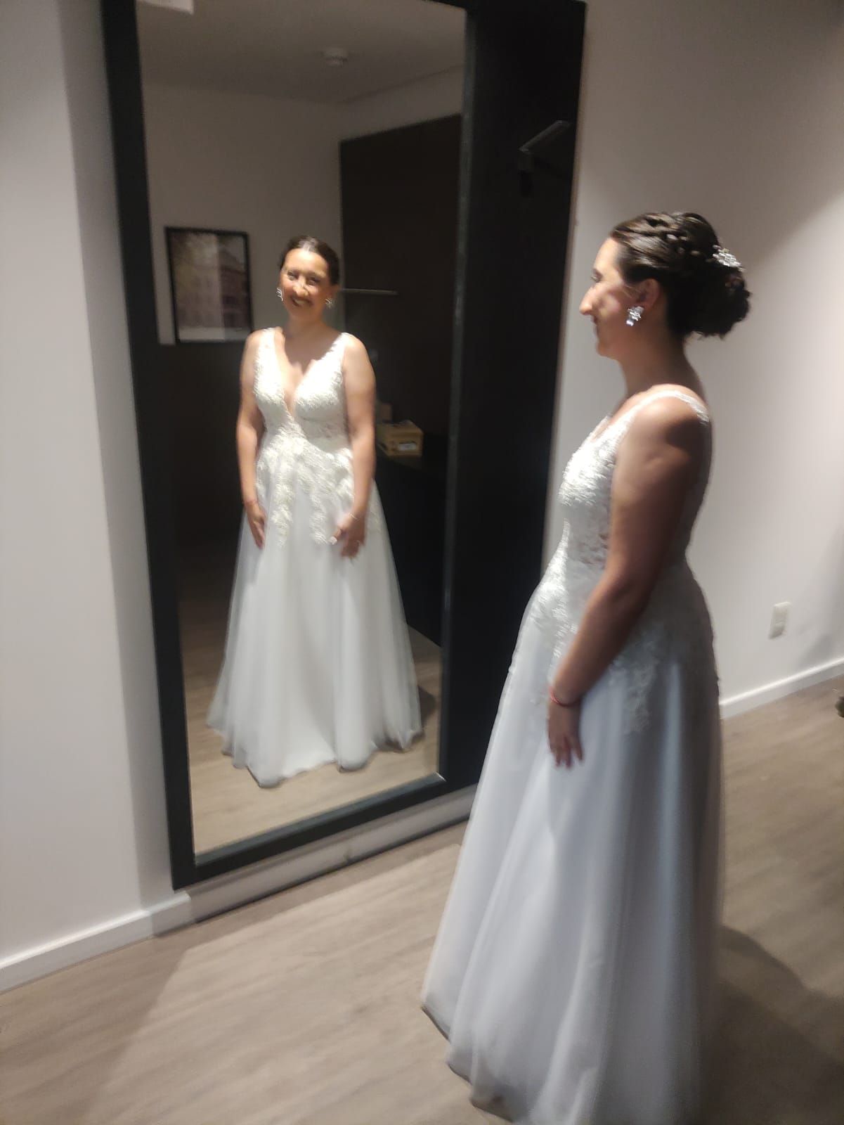 Una mujer con un vestido blanco está parada frente a un espejo.