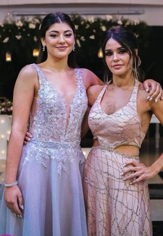 Dos mujeres con vestidos posan juntas para una fotografía.