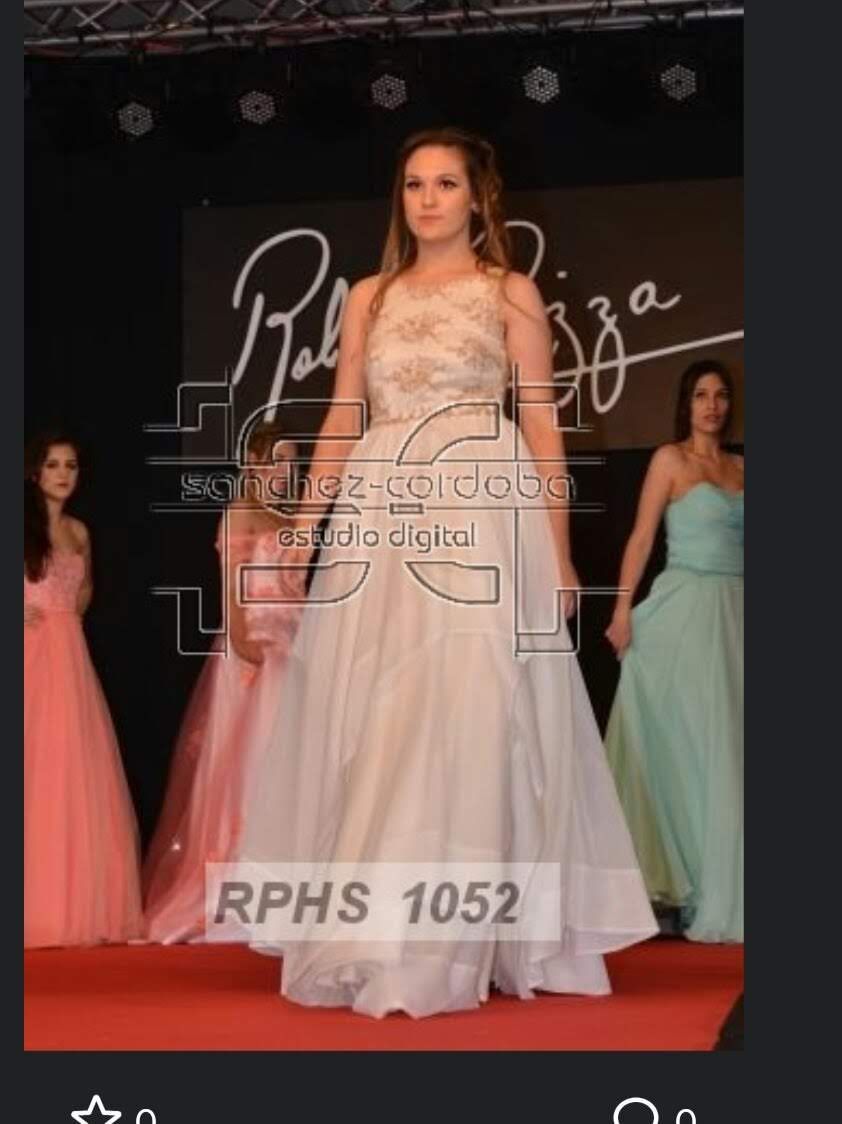 Mujer con vestido formal en una pasarela con otras modelos. Fondo de evento con logotipo y alfombra roja.