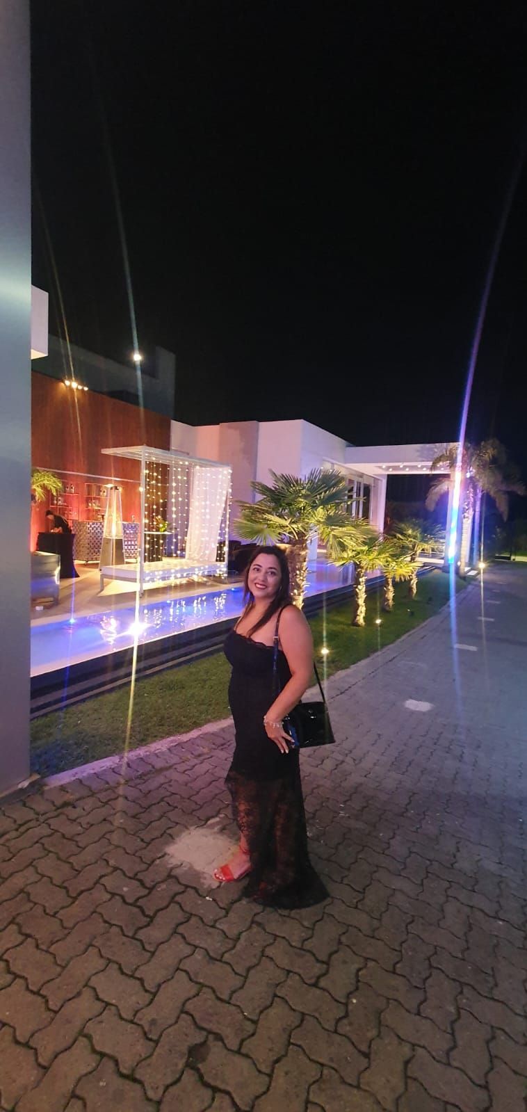 Una mujer con un vestido negro está parada frente a un edificio por la noche.