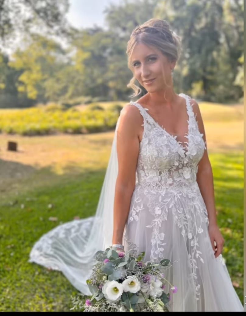 Una mujer con un vestido de novia sostiene un ramo de flores.