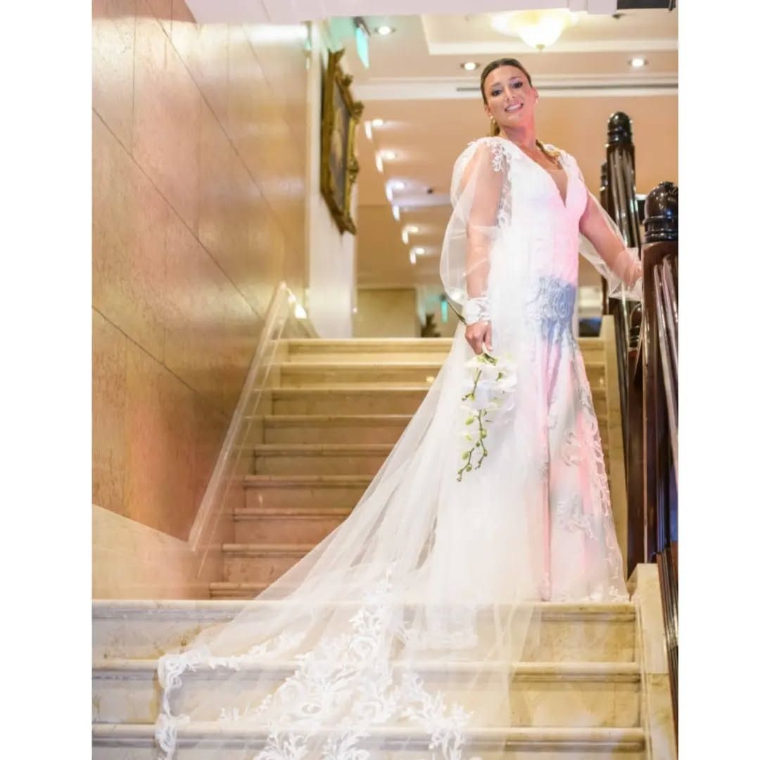 Una mujer con un vestido de novia está de pie en unas escaleras.