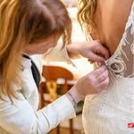 Mujer abrocha botones en un vestido de novia, en el interior.