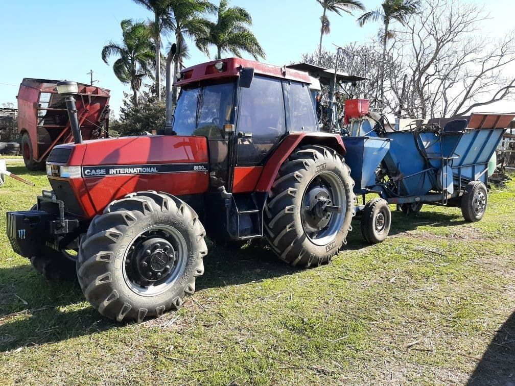 A Red Tractor With A Blue Trailer Attached To It Is Parked In A Grassy Field — Ace-Marian In Walkerston, QLD