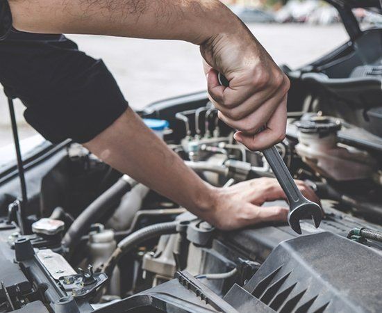 A Man Is Working On A Car Engine With A Wrench — Ace-Marian In Marian, QLD