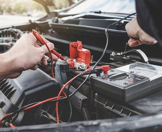 A Man Is Working On A Car Battery With A Multimeter — Ace-Marian In Marian, QLD