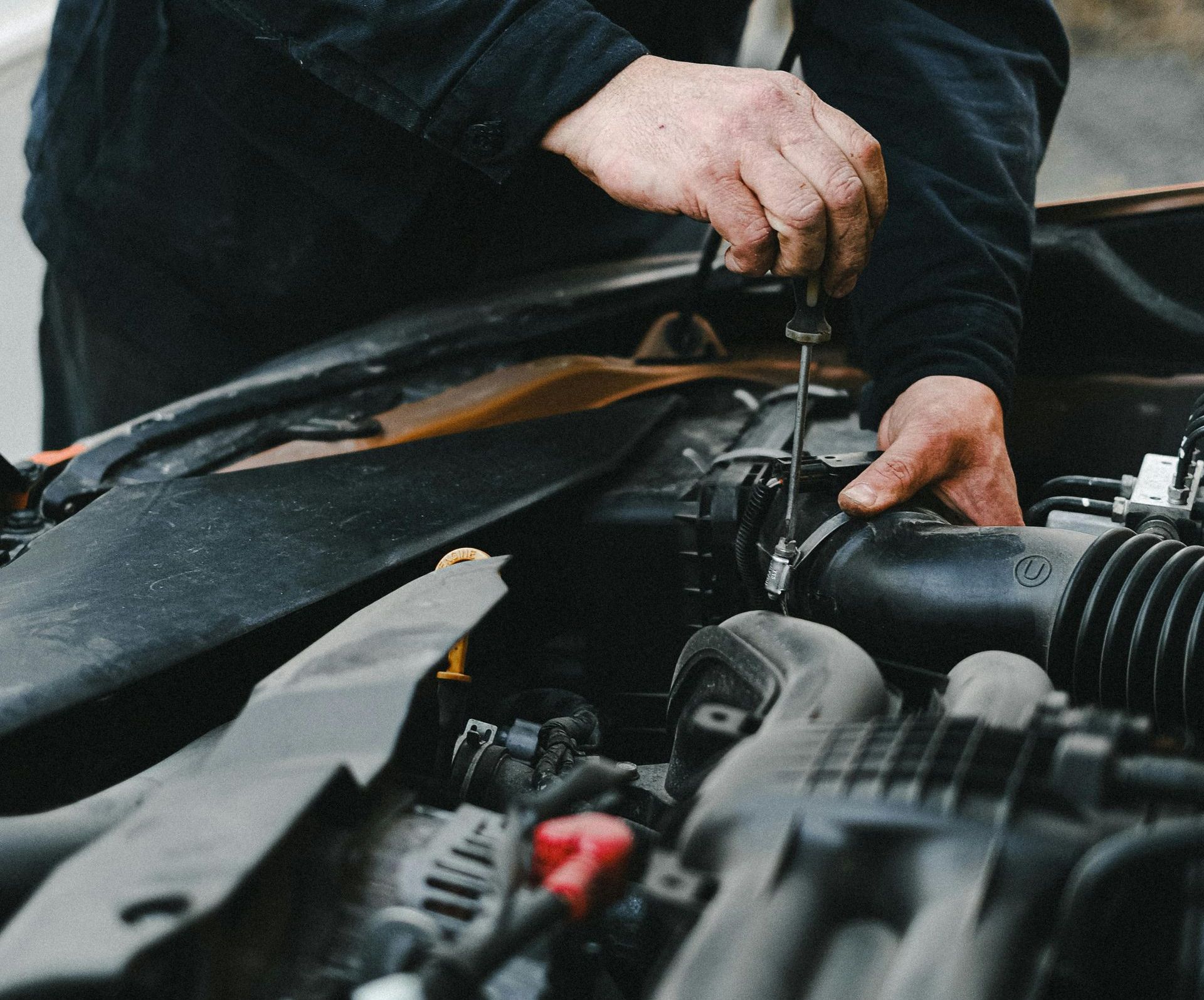 A Man Is Working On A Car Battery In A Garage — Ace-Marian In Marian, QLD