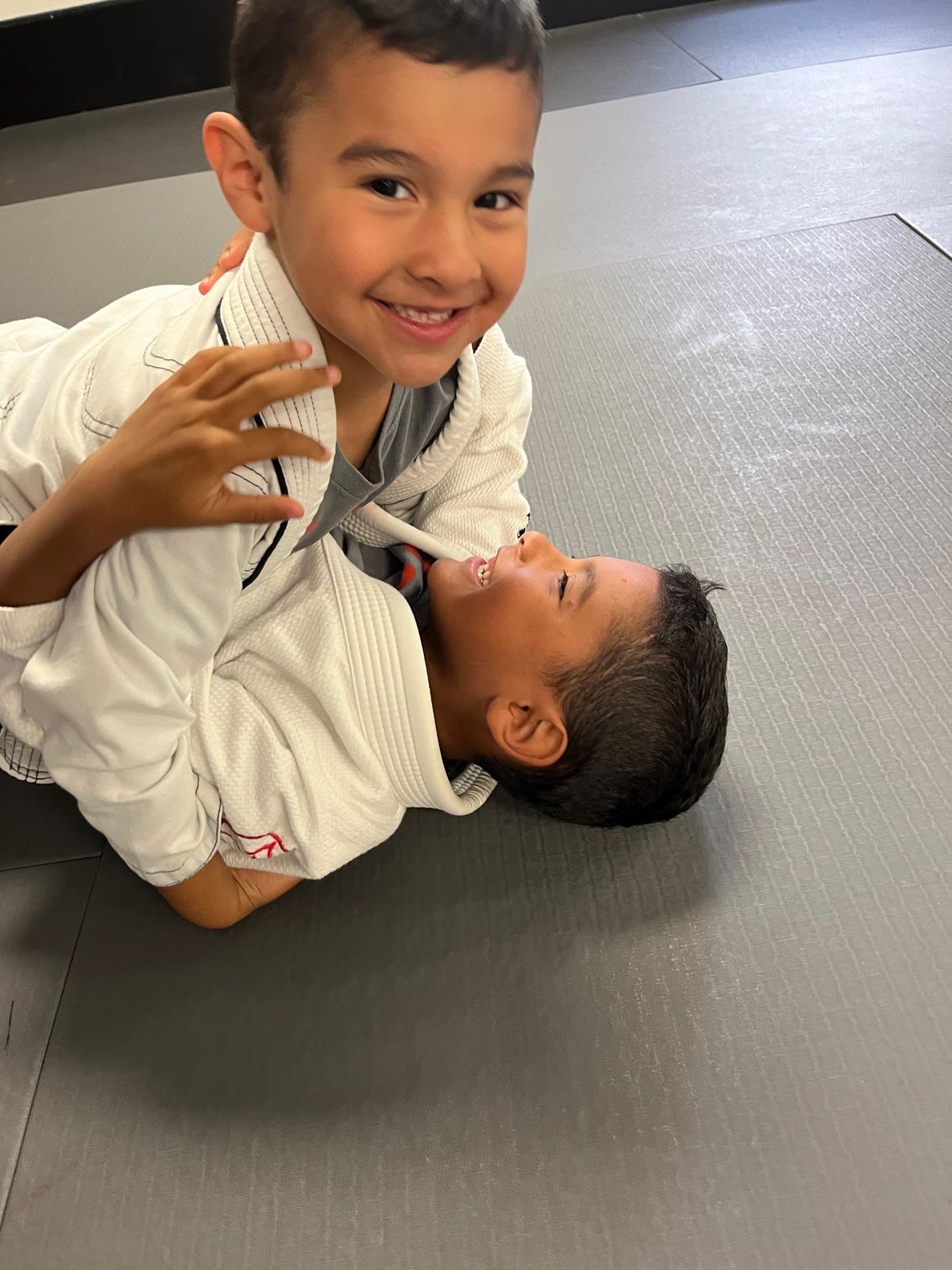 2 boys smiling and training grappling together.