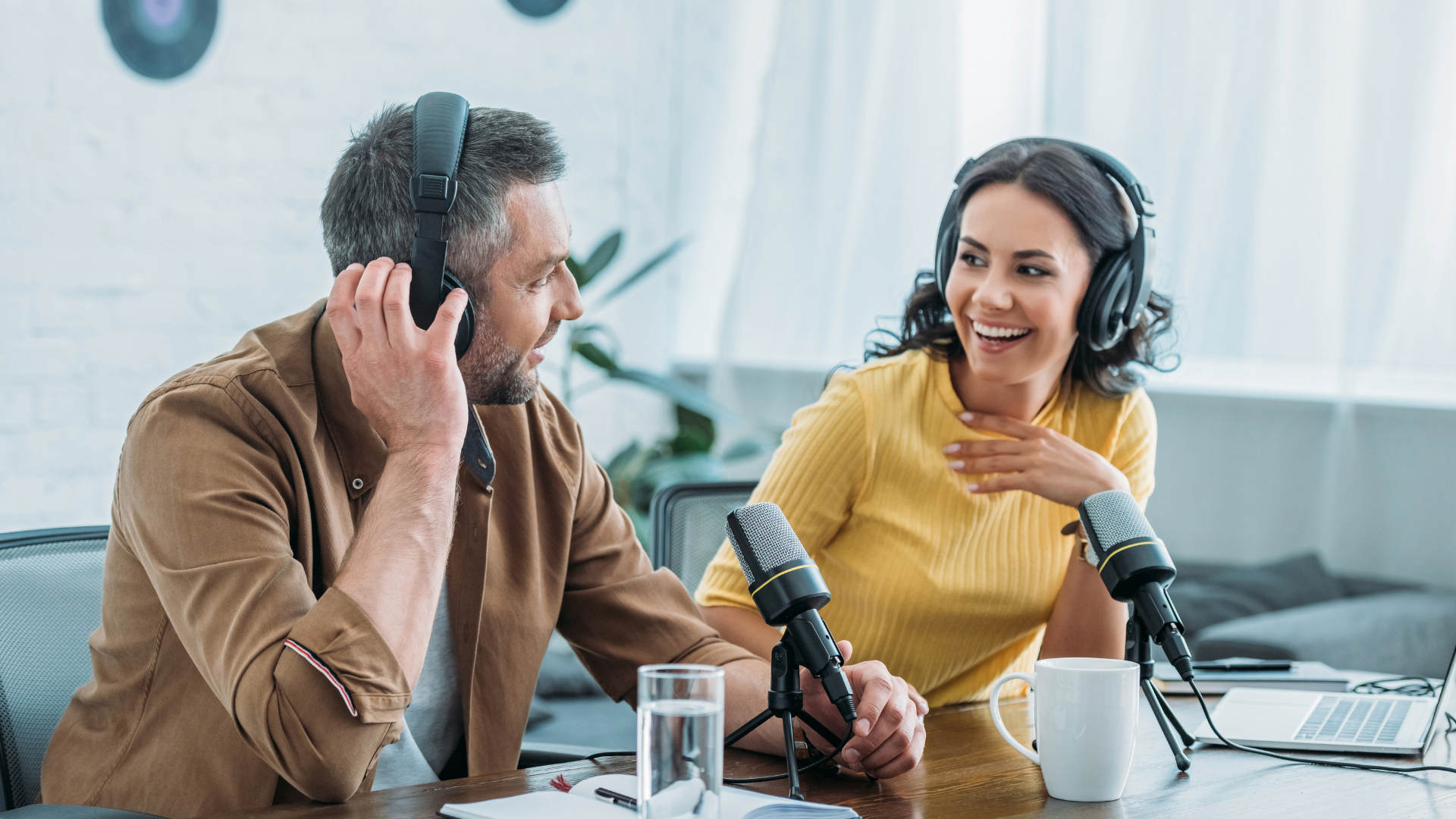 A man and a woman are sitting at a table talking into microphones.