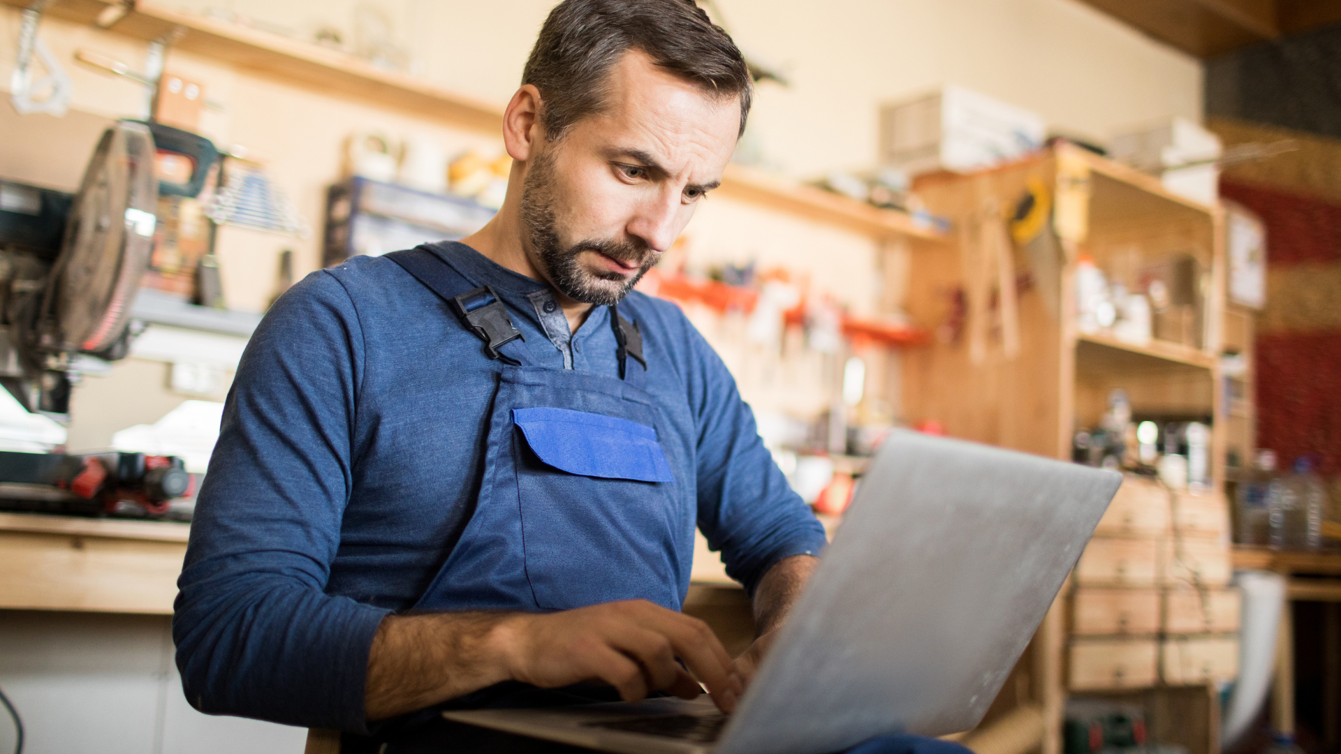 A man is using a laptop computer in a garage.