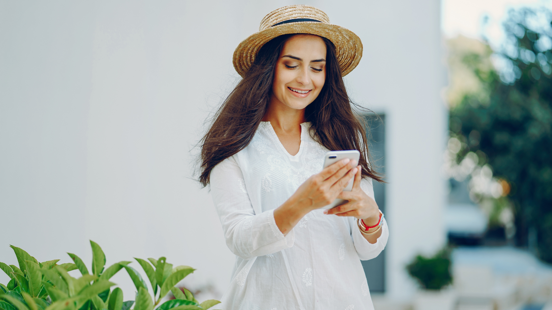 A woman in a straw hat is using a cell phone.