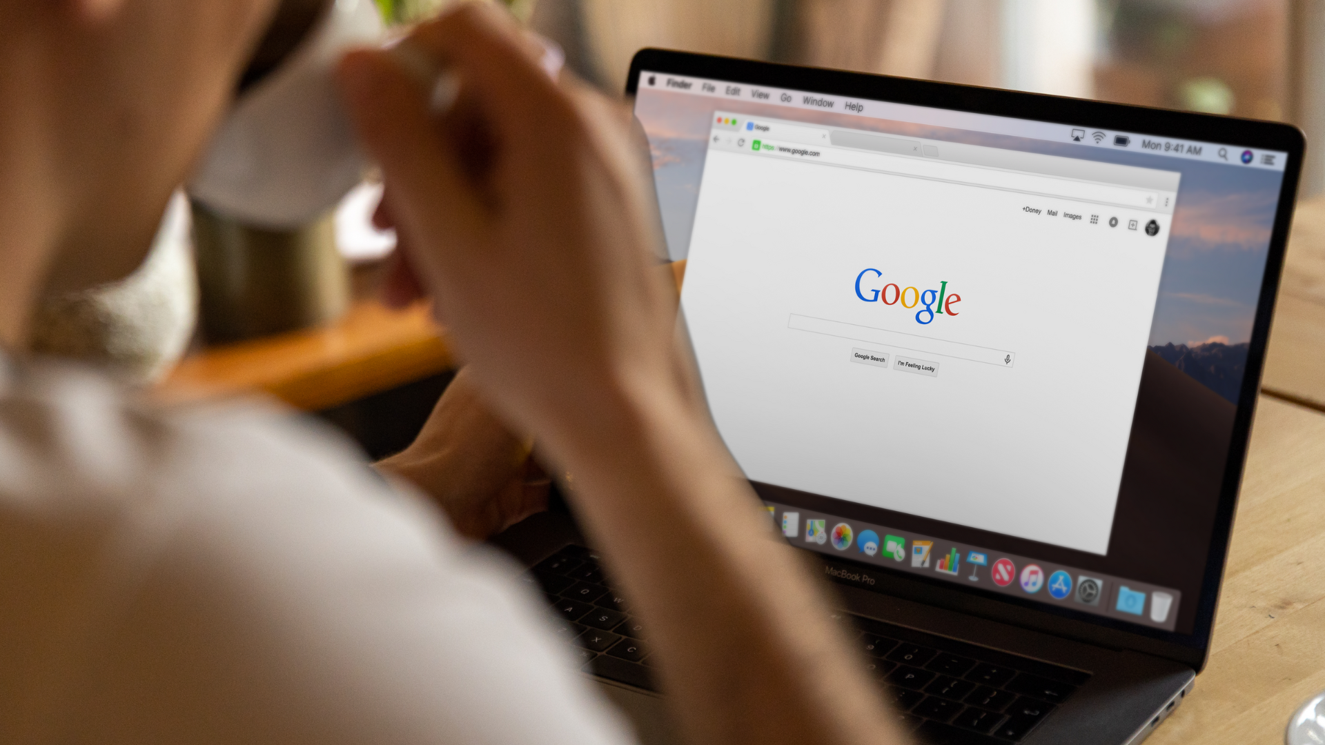 A person is using a laptop computer while holding a cup of coffee.