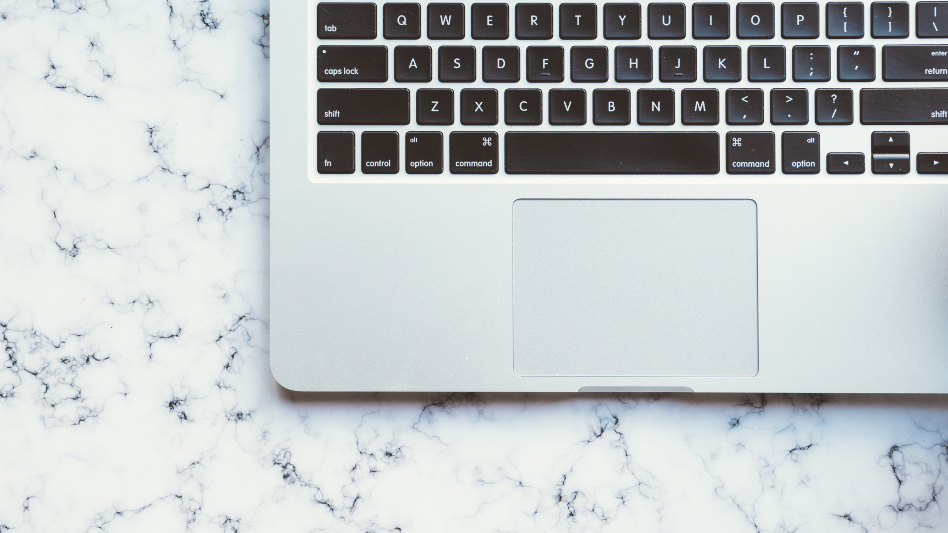 Laptop on white marble surface. Keyboard and trackpad visible.