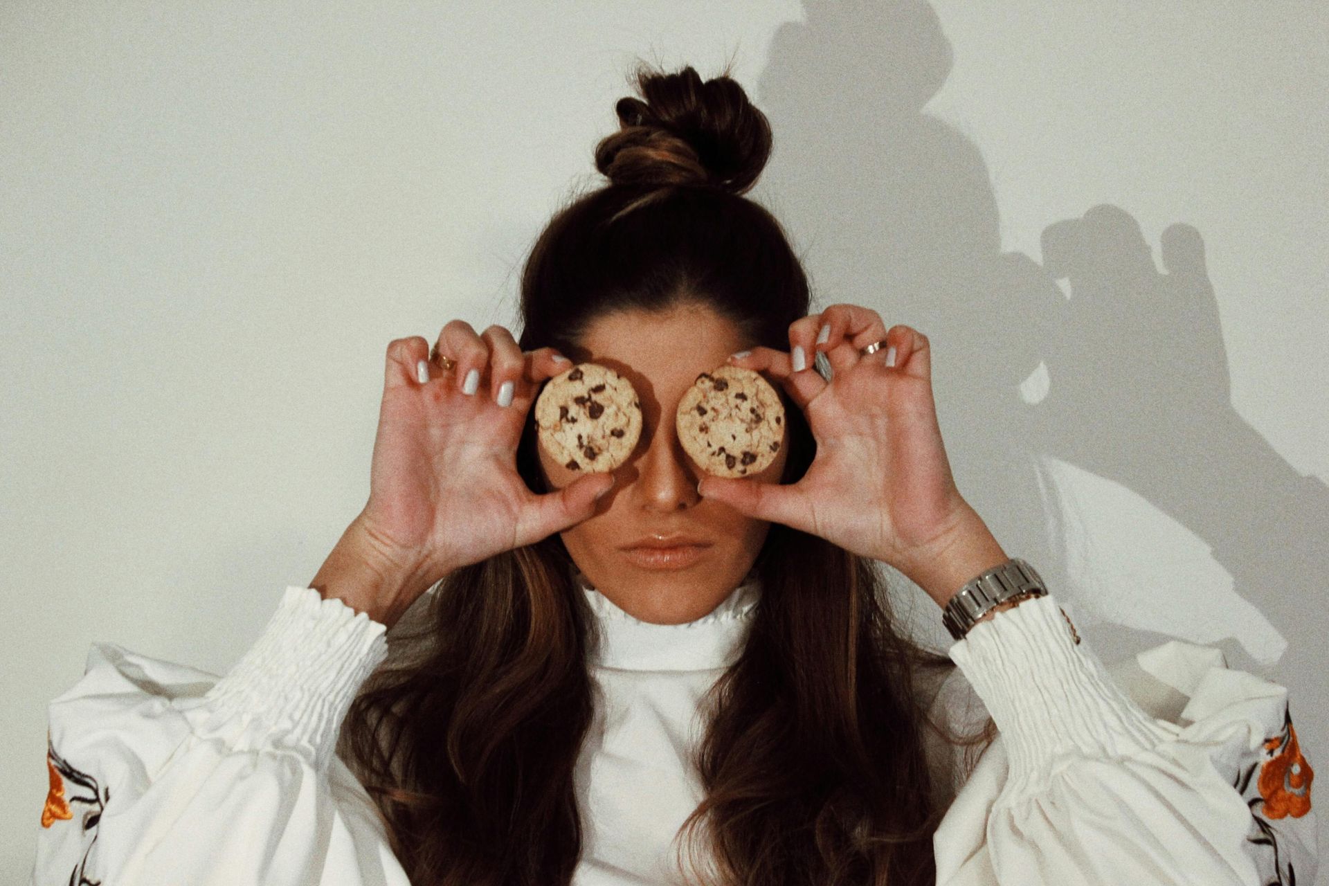 Une femme tient deux biscuits devant ses yeux.