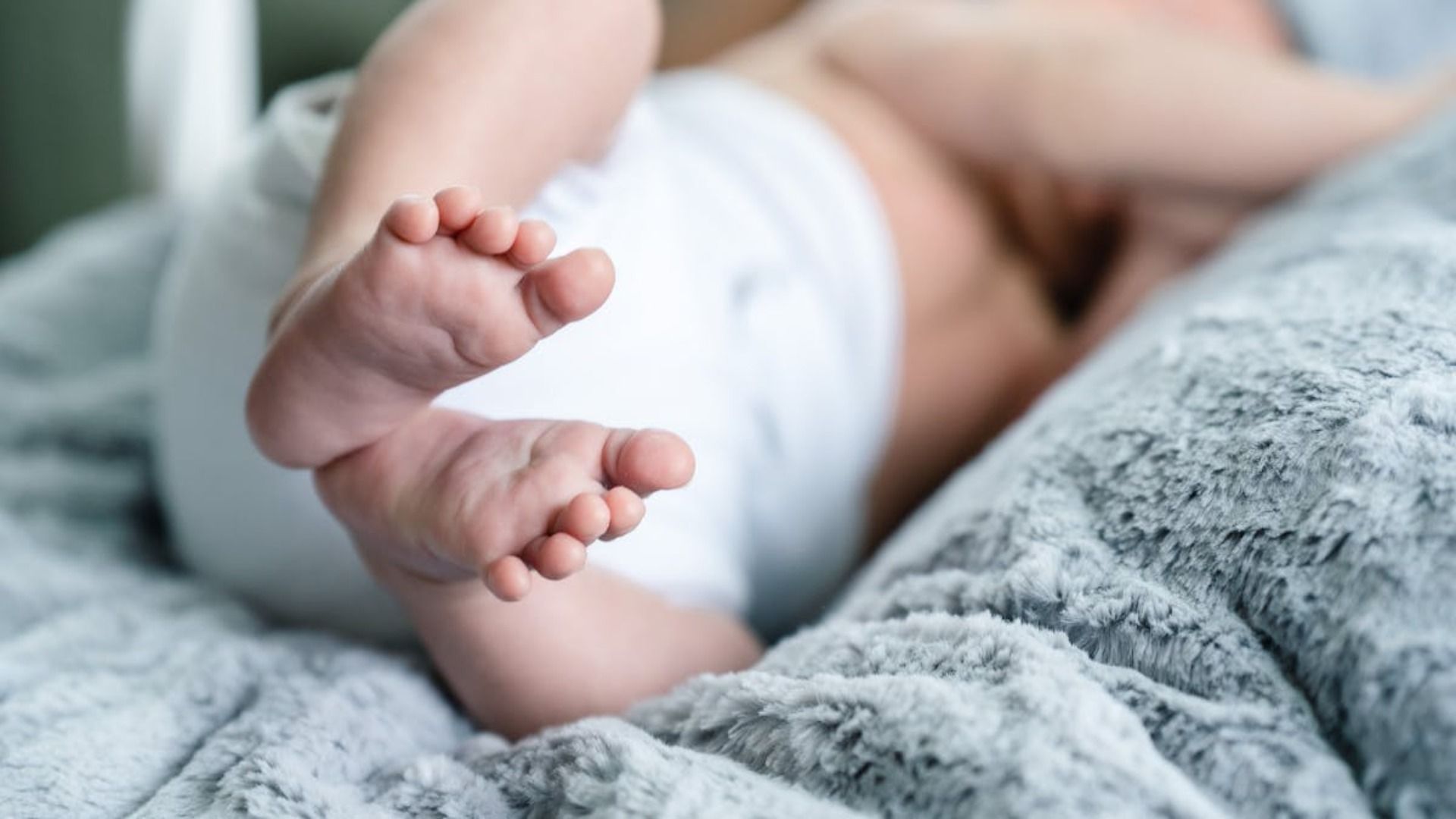 Un primer plano de los pies de un bebé acostado en una cama.
