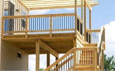 Spacious multi-level wooden deck construction with modern railings by Forest City Decks in a Rockford, IL backyard.