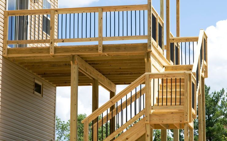 Newly constructed natural wood multi-tier deck with sturdy railings and stairway in Rockford, IL, showcasing expert carpentry by local builders.
