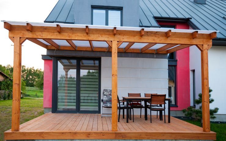 Newly constructed wooden deck and pergola outside a modern Rockford home, providing an elegant outdoor dining area.