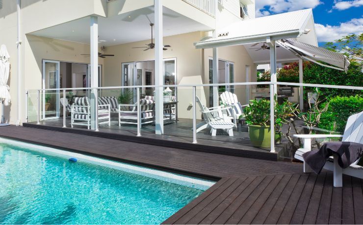 Luxurious pool deck in Rockford, IL, featuring composite decking with sleek glass railing and stylish outdoor furniture for a chic relaxation area.