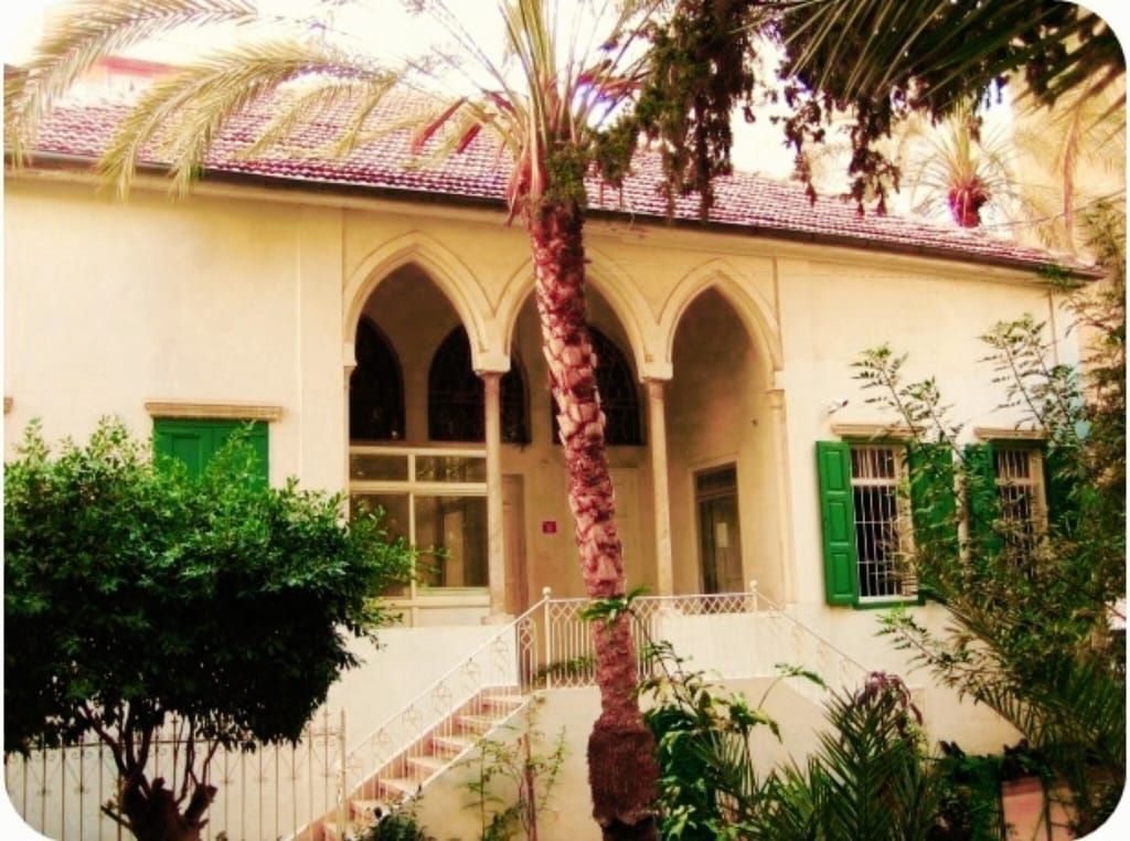 macromed. pharmaceutical compnanies in lebanon. rabih hassouneh. A white house with green shutters and a palm tree in front of it