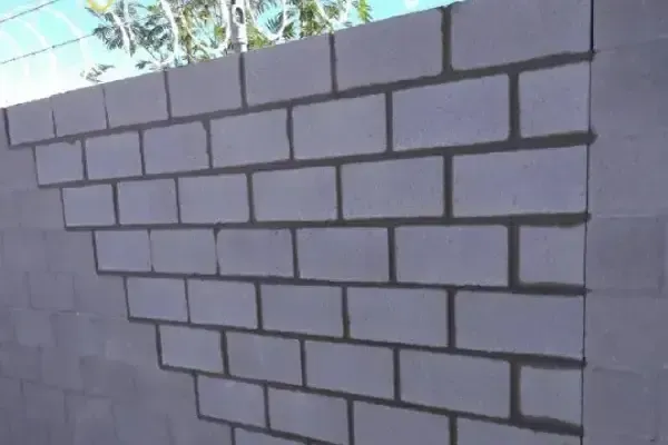 Partially painted concrete block wall with dark mortar lines outdoors