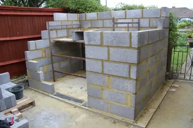 Partially built cinder block outdoor oven or fireplace in a backyard under construction