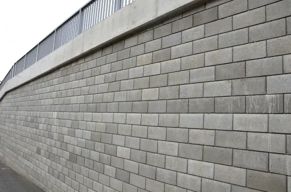 Gray concrete block retaining wall curving into the distance along a road or path