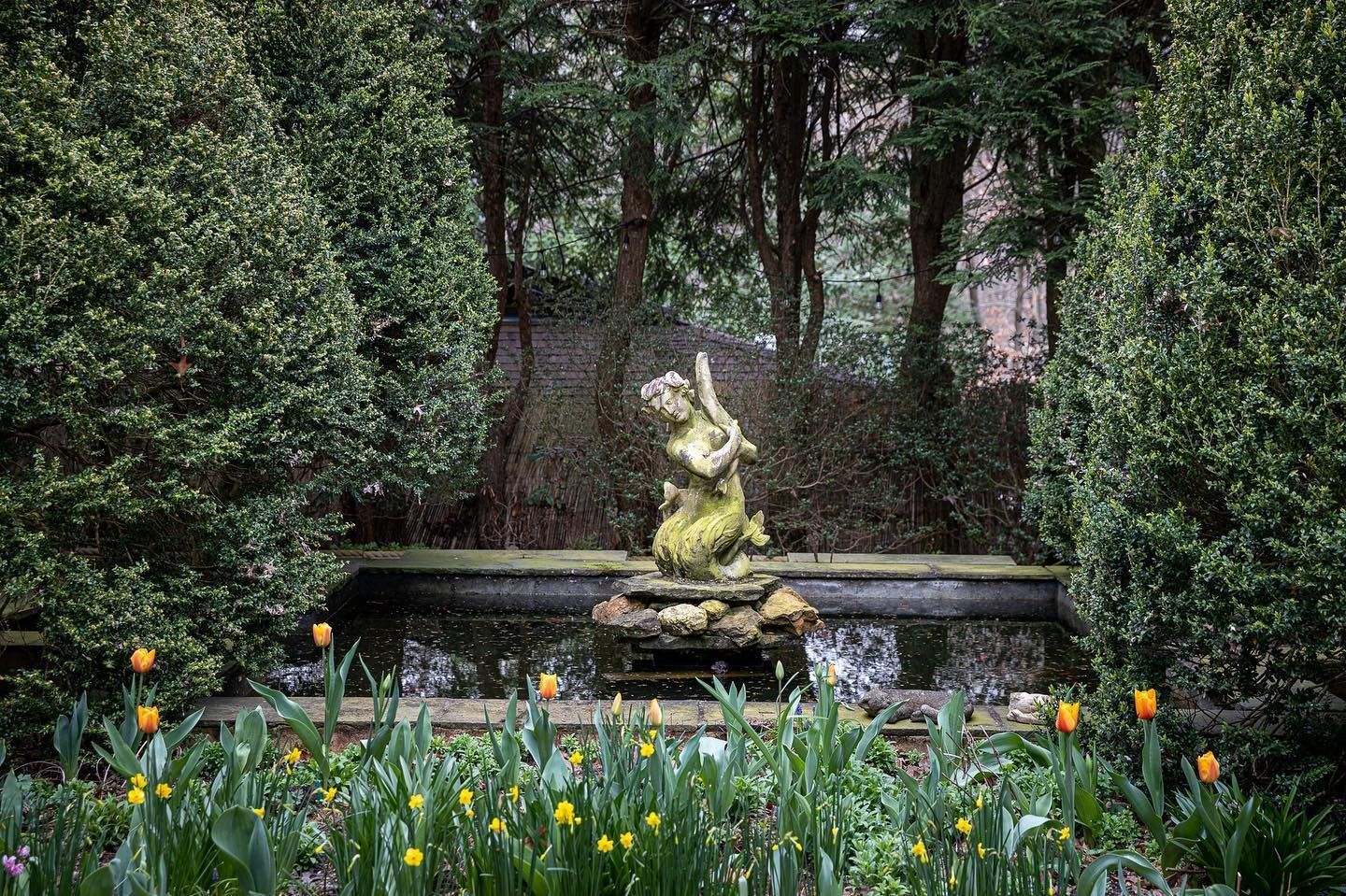 A stone statue of a cherub in a pond.