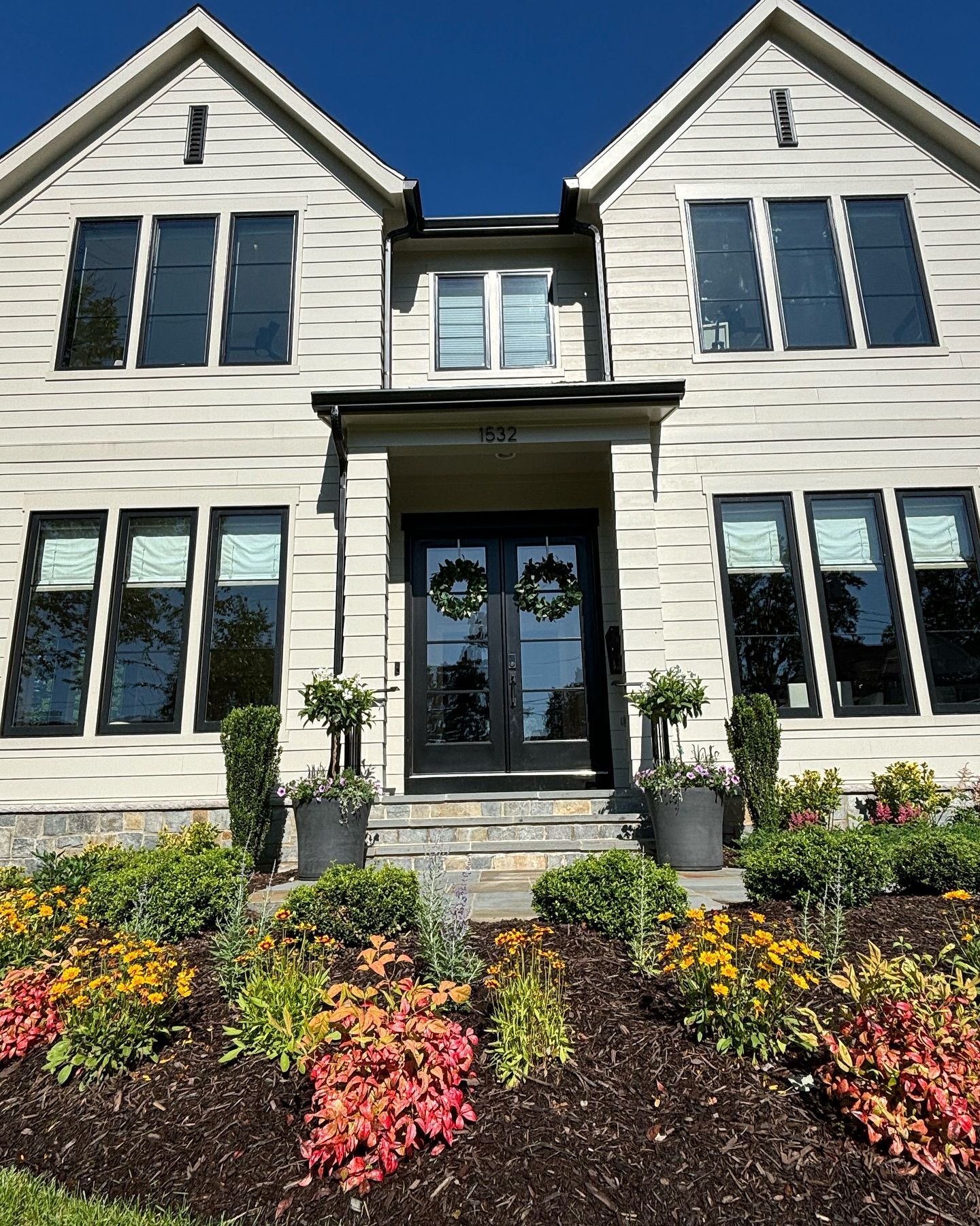A two-story house with cream horizontal siding, dark window frames.