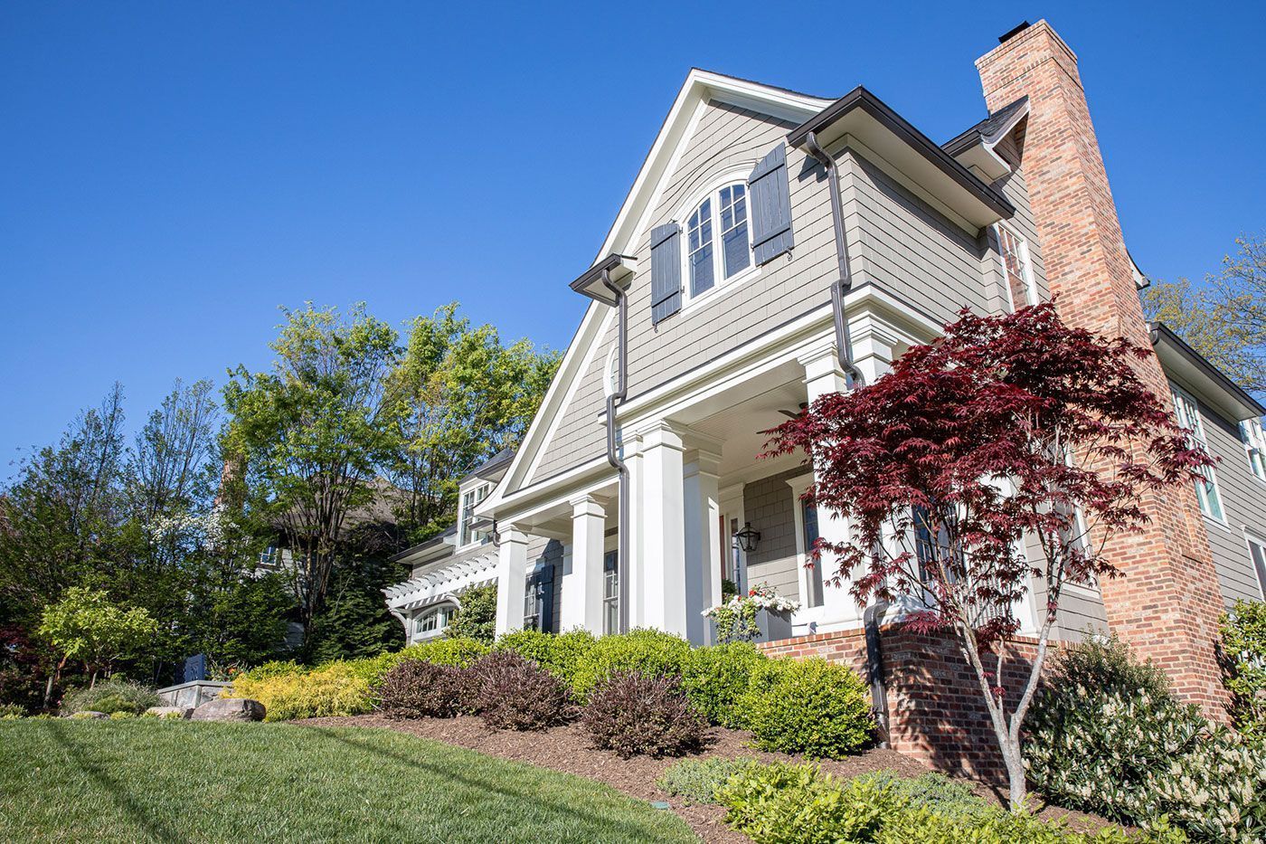 A two-story grey shingled house with white columns.
