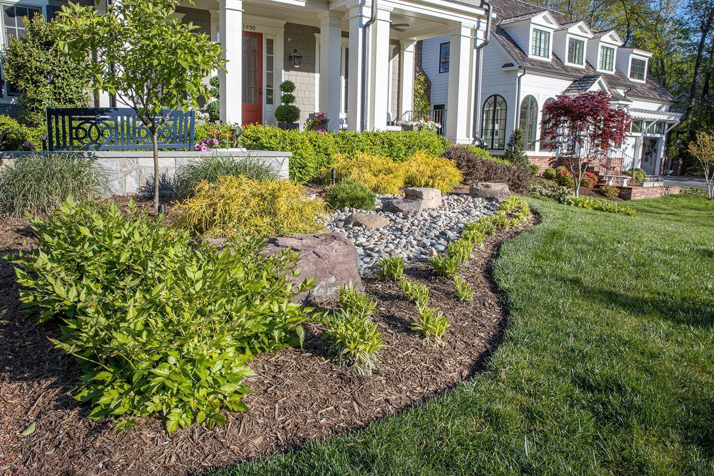 A landscaped yard features a curved garden bed with shrubs.