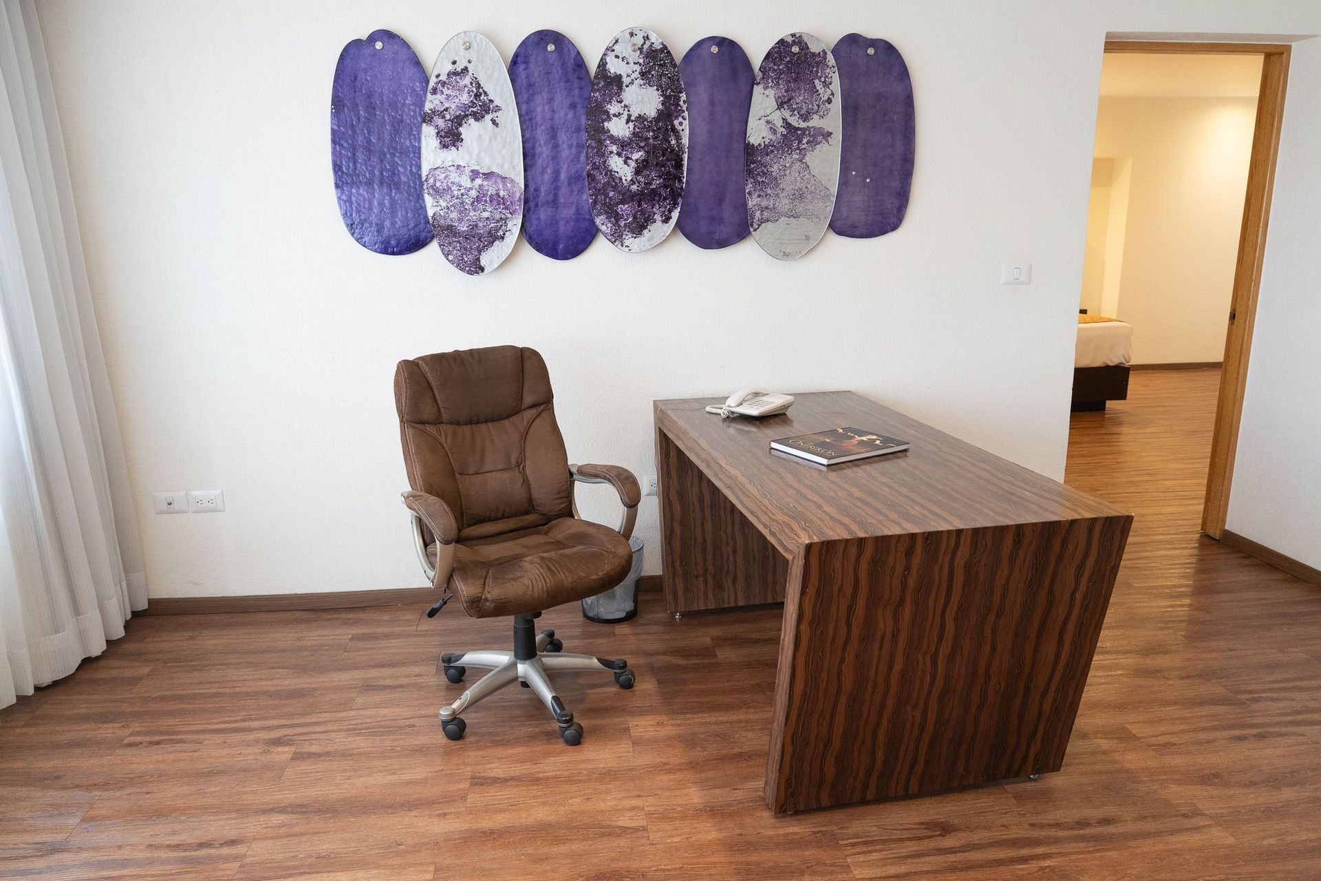 Una silla de oficina marrón se encuentra frente a un moderno escritorio de madera 