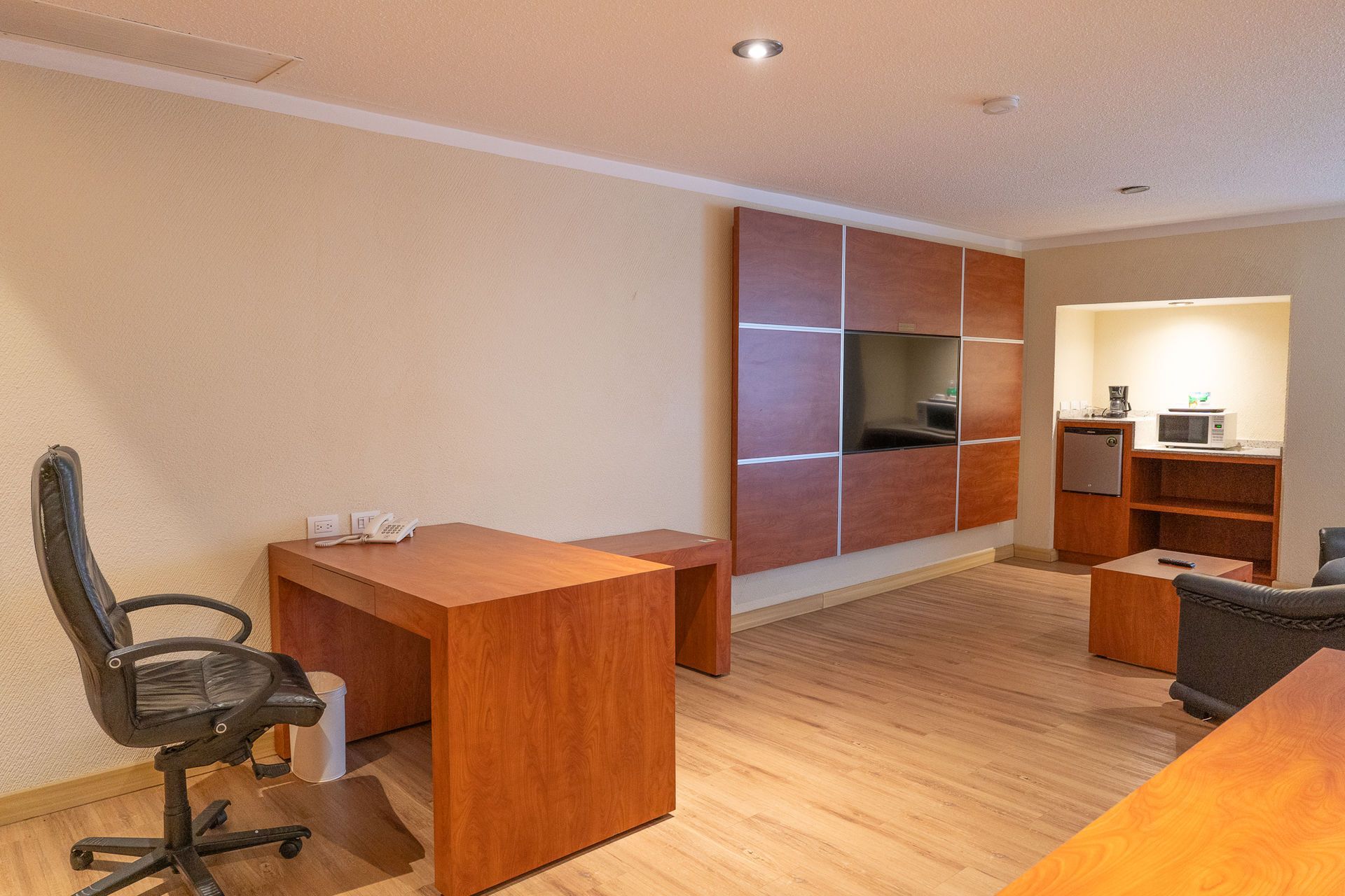 Una habitación de hotel con escritorio de madera y silla de oficina negra