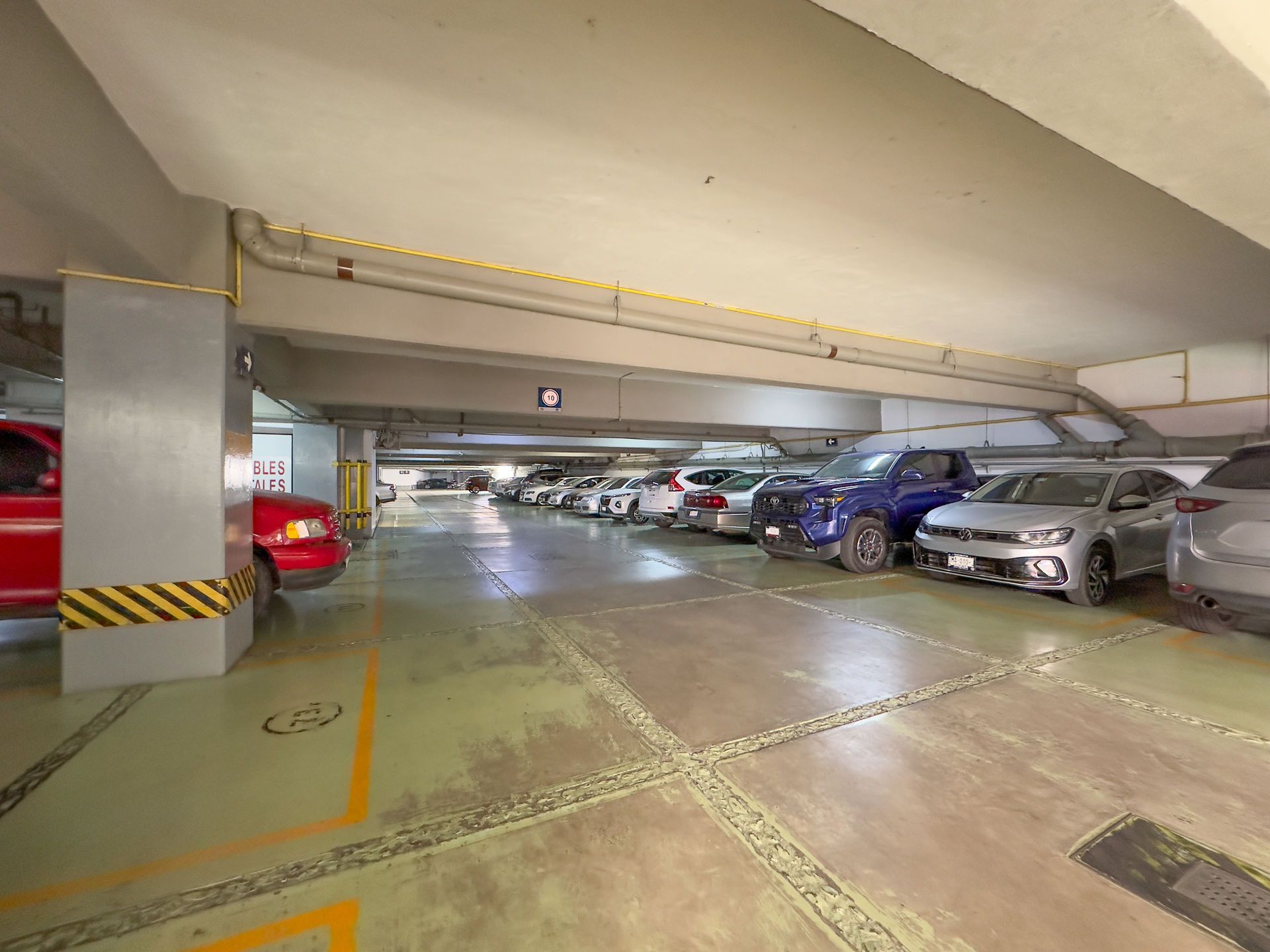 Aparcamiento cubierto con una fila de coches aparcados 