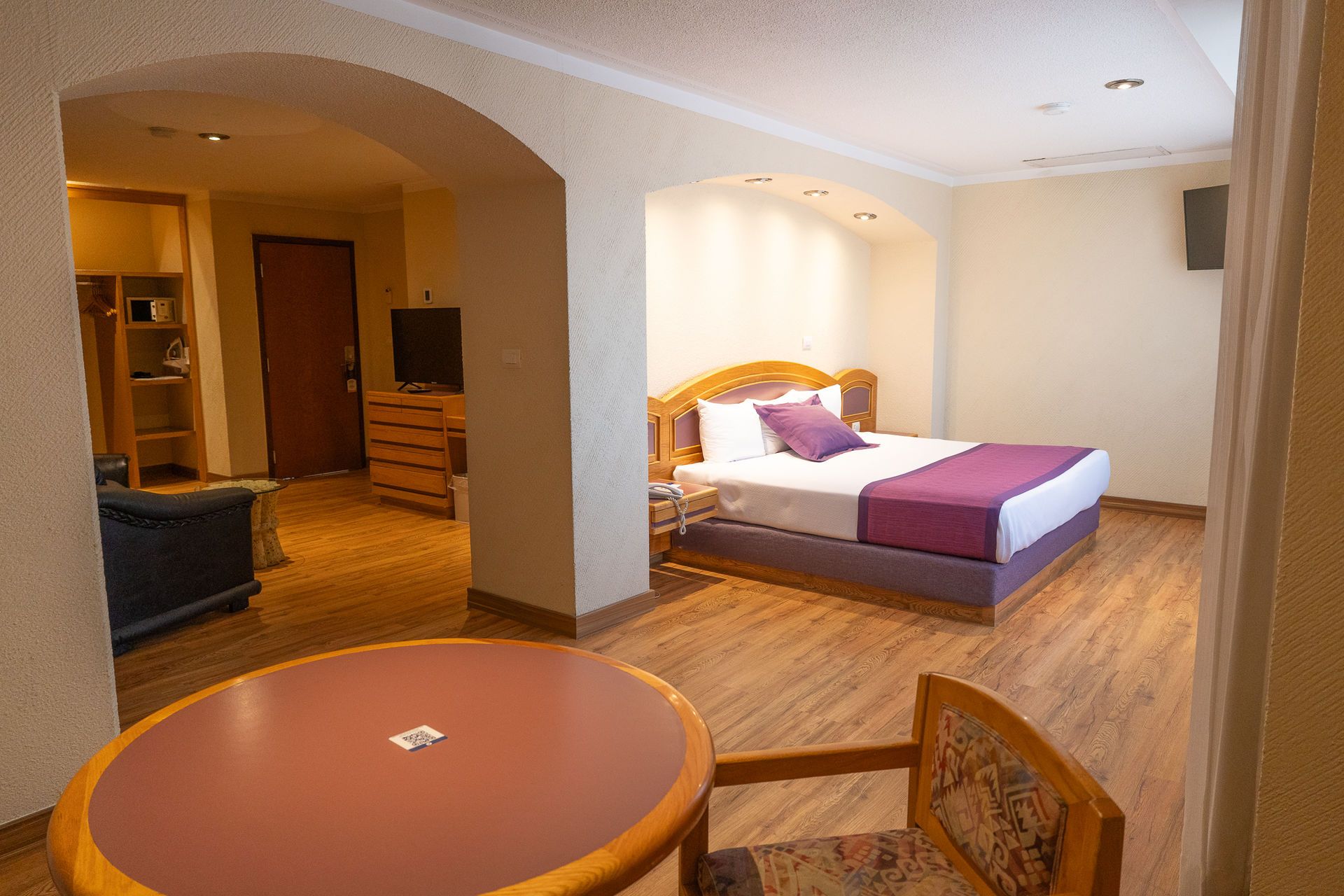 Una espaciosa habitación de hotel con una cama de madera con un camino de mesa morado