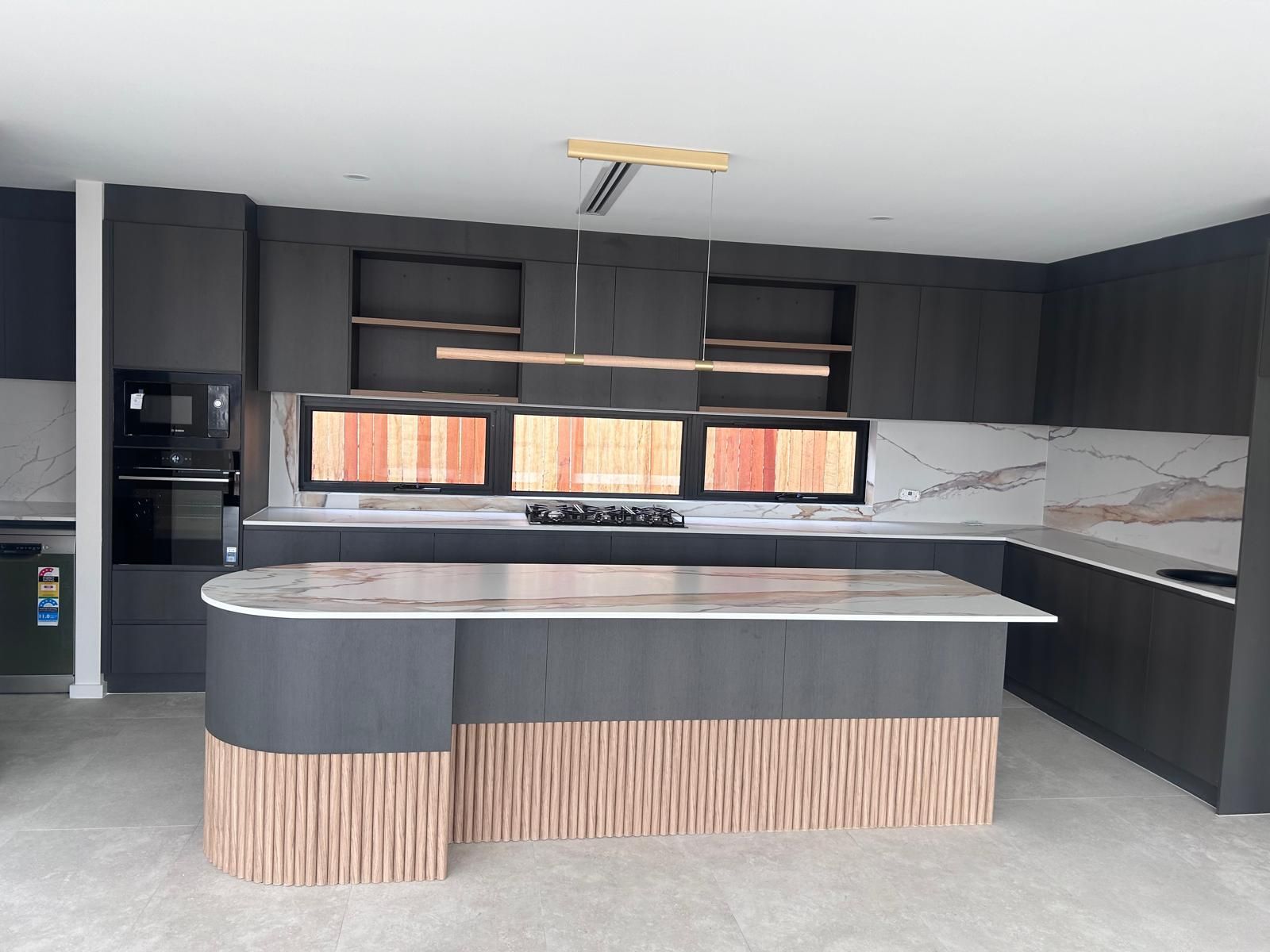 A kitchen with black cabinets and a large island in the middle.