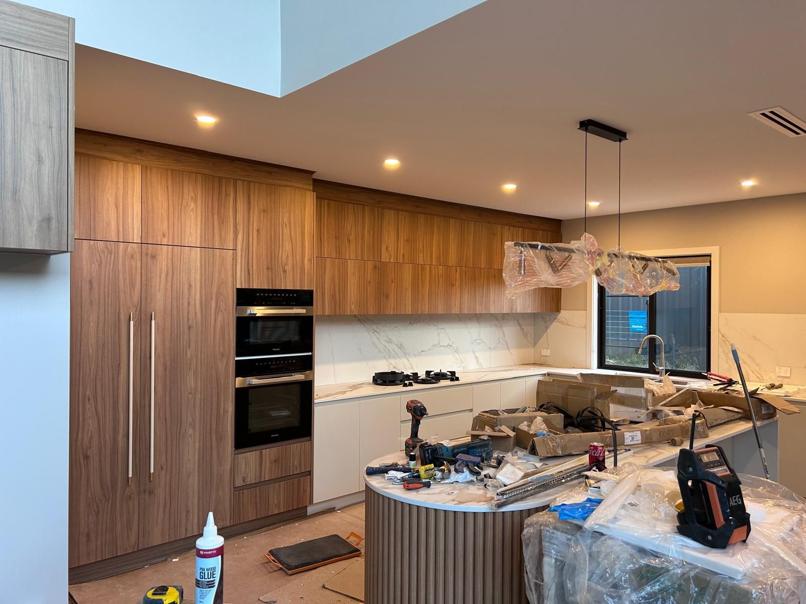 A kitchen under construction with wooden cabinets and a marble counter top.