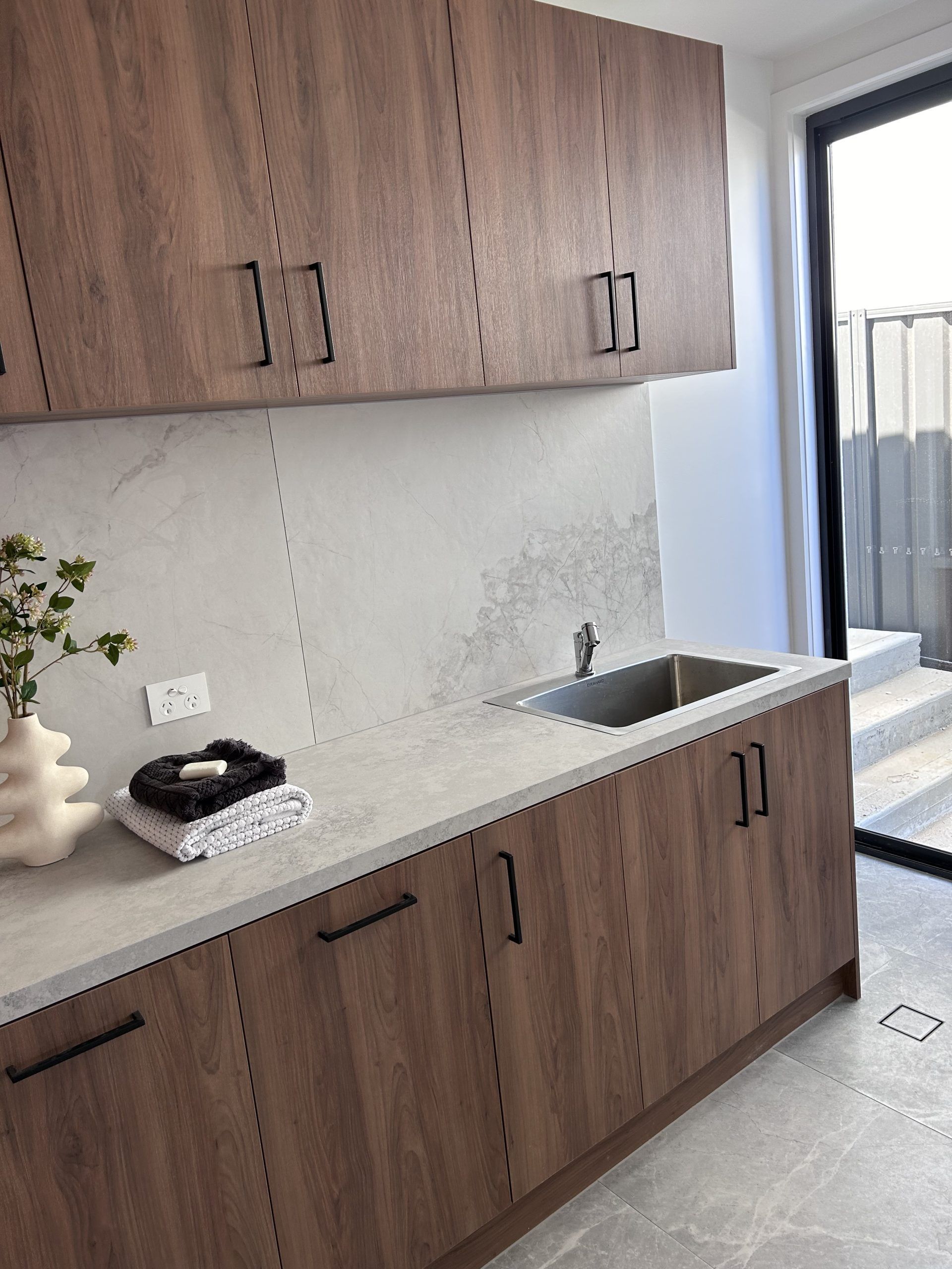 A kitchen with wooden cabinets , a sink , and a sliding glass door.