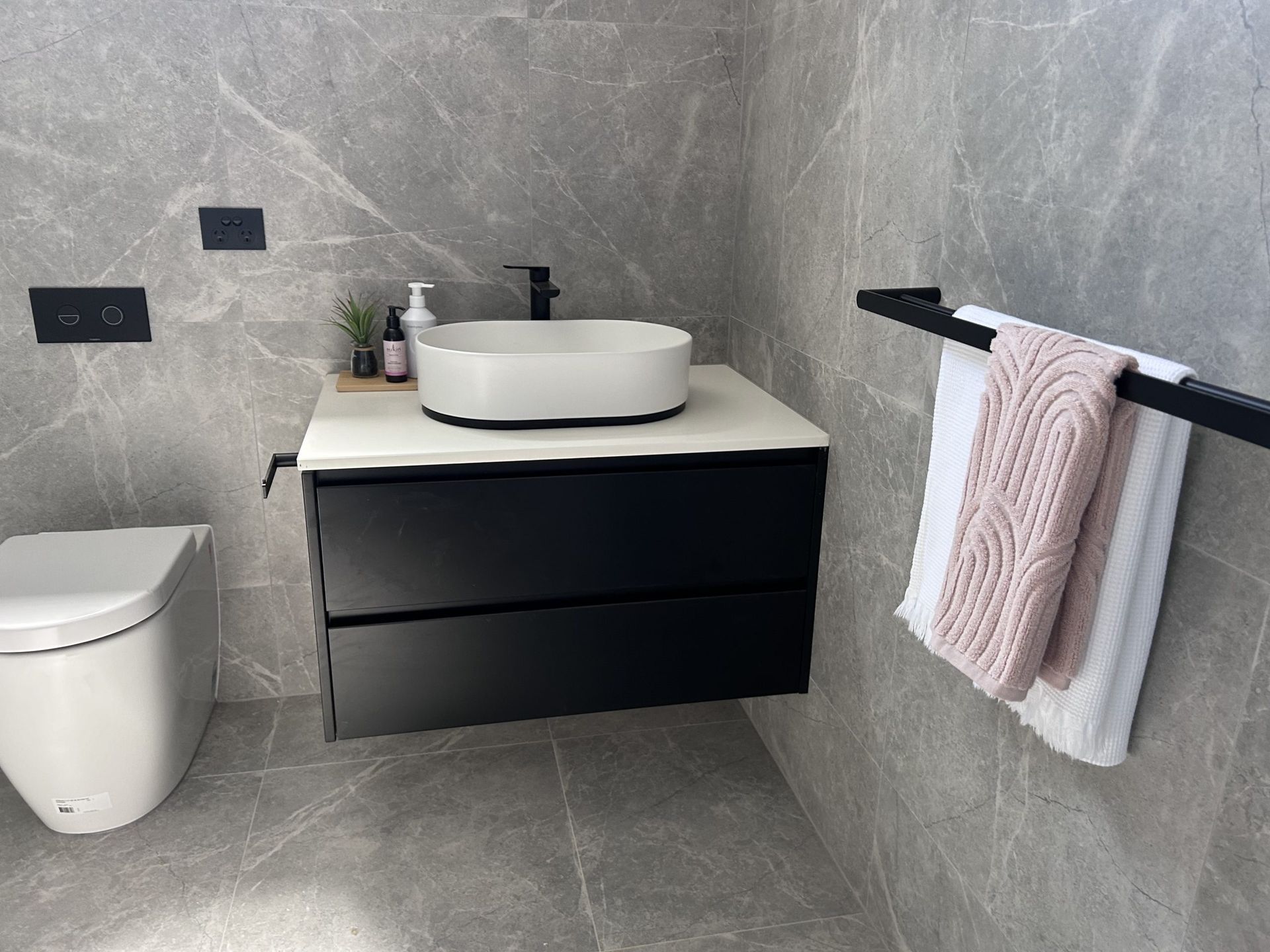 A bathroom with a toilet , sink , and towel rack.