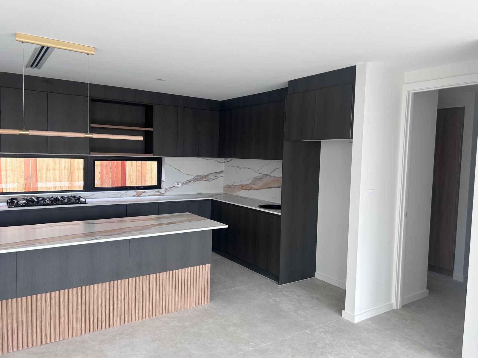 A kitchen with black cabinets and a marble counter top.