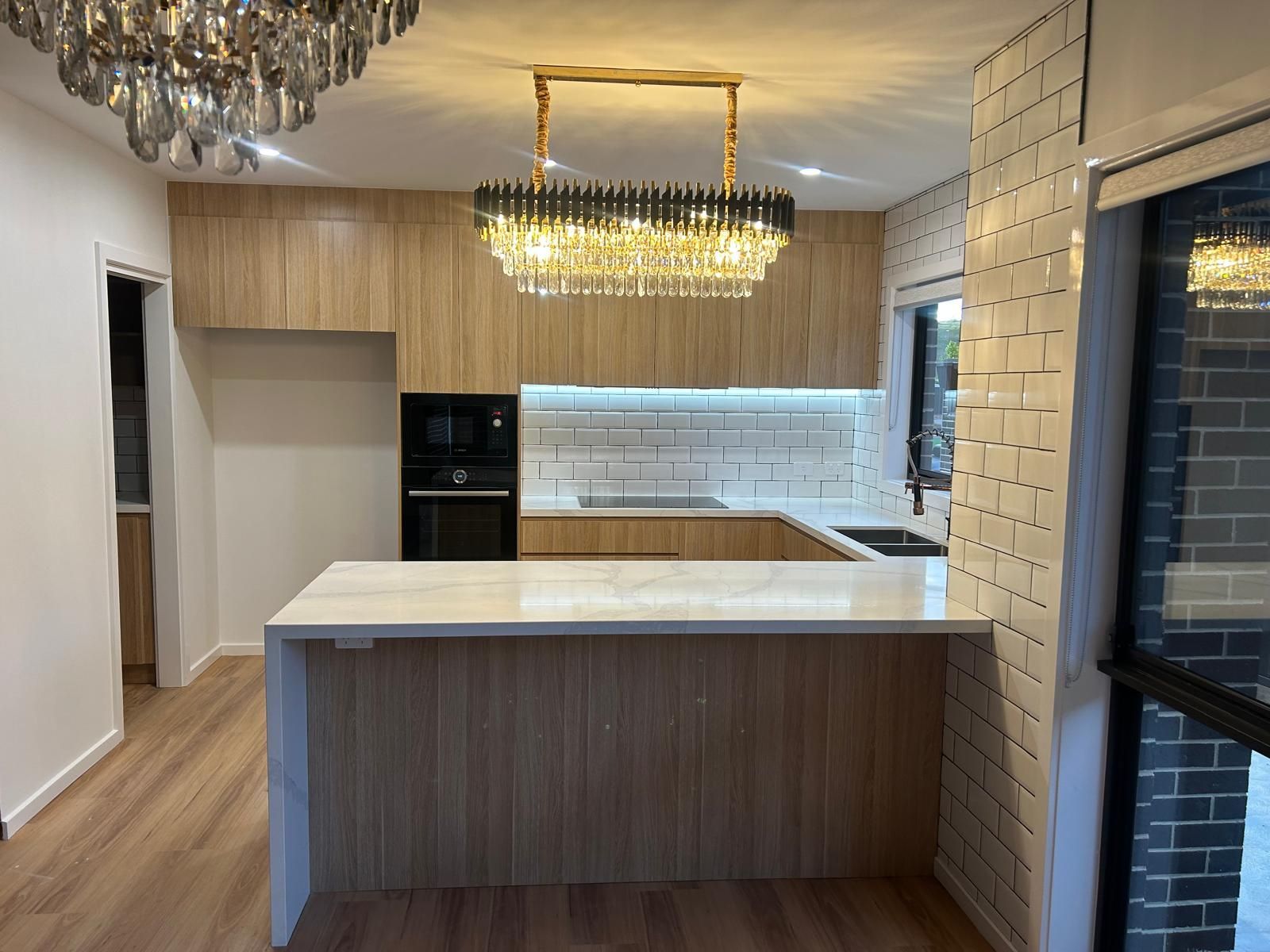 A kitchen with a large island and a chandelier hanging from the ceiling.