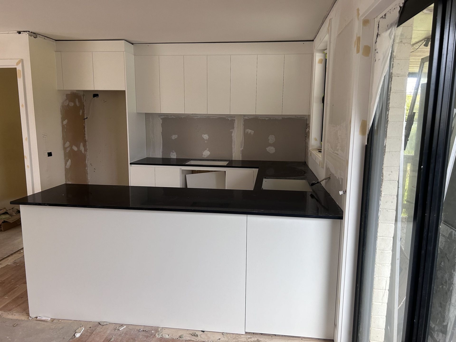 A kitchen with white cabinets and a black counter top.