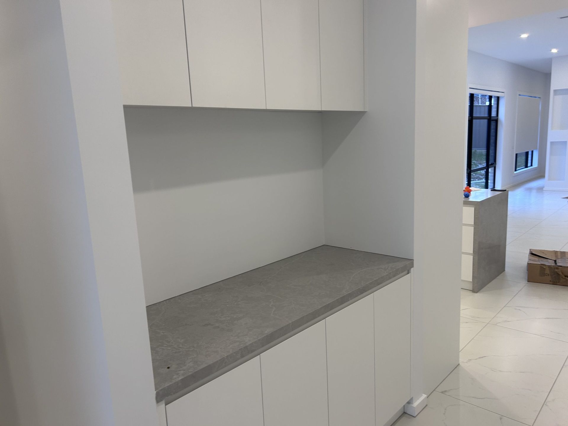 A kitchen with white cabinets and a gray counter top.