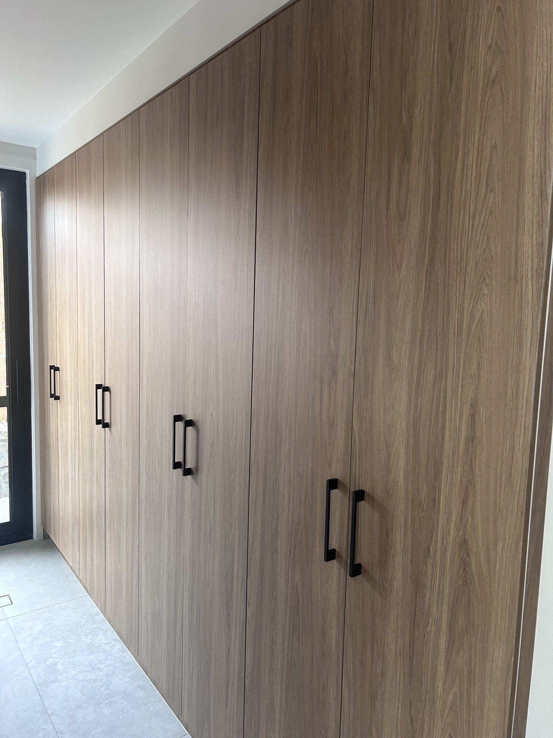 A row of wooden cabinets with black handles in a room.