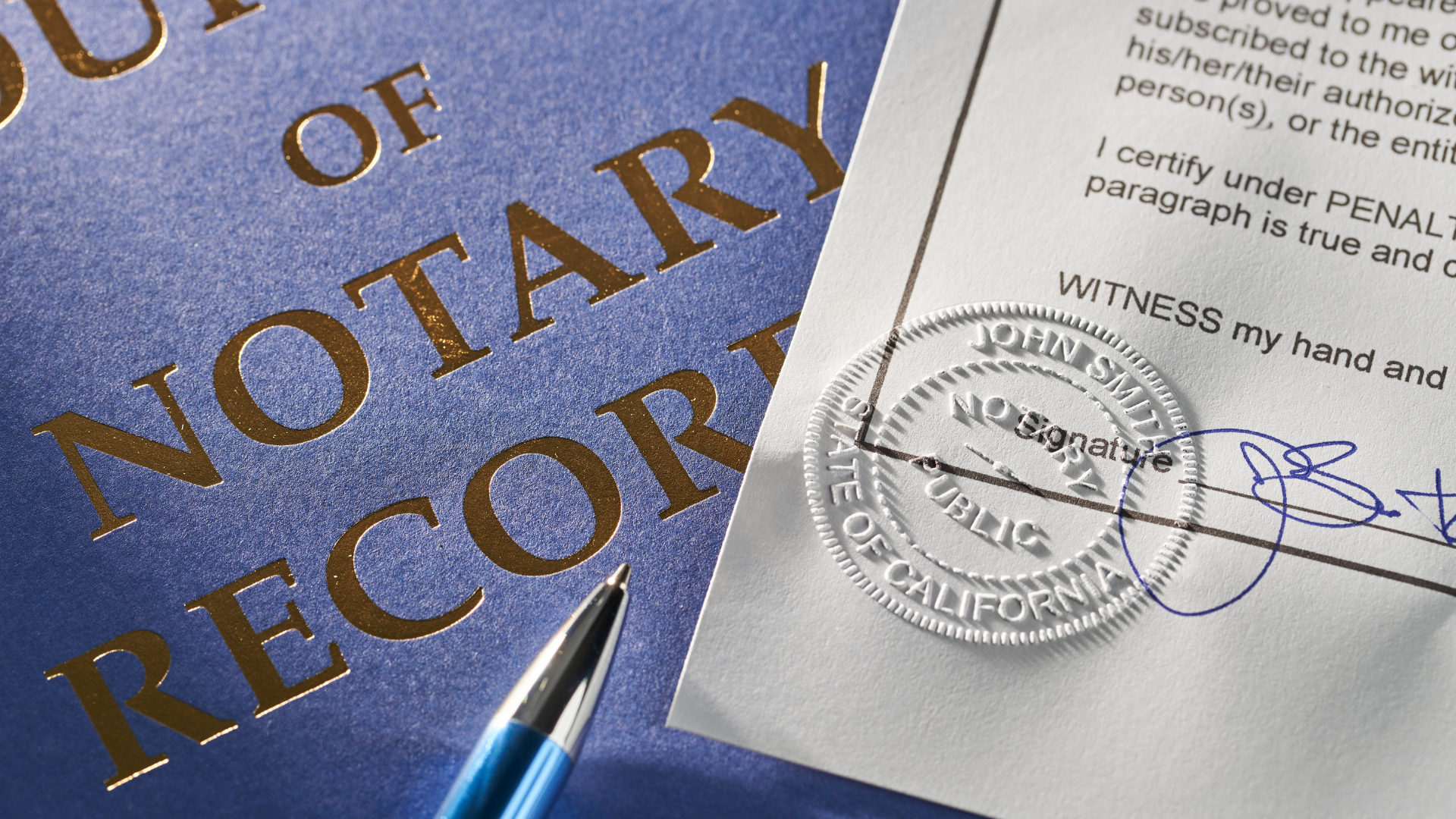 Notary record book beside a signed document with an embossed seal and pen