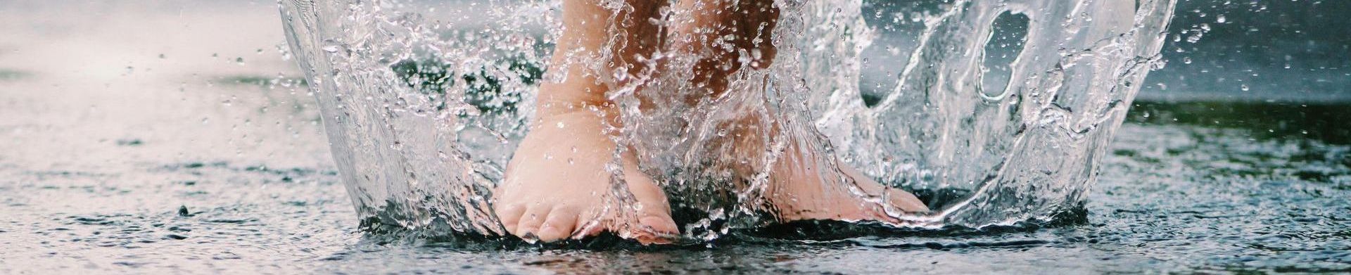 Kleine Brücke aus Baumstämmen überspannt einen flachen Graben im Erdreich.