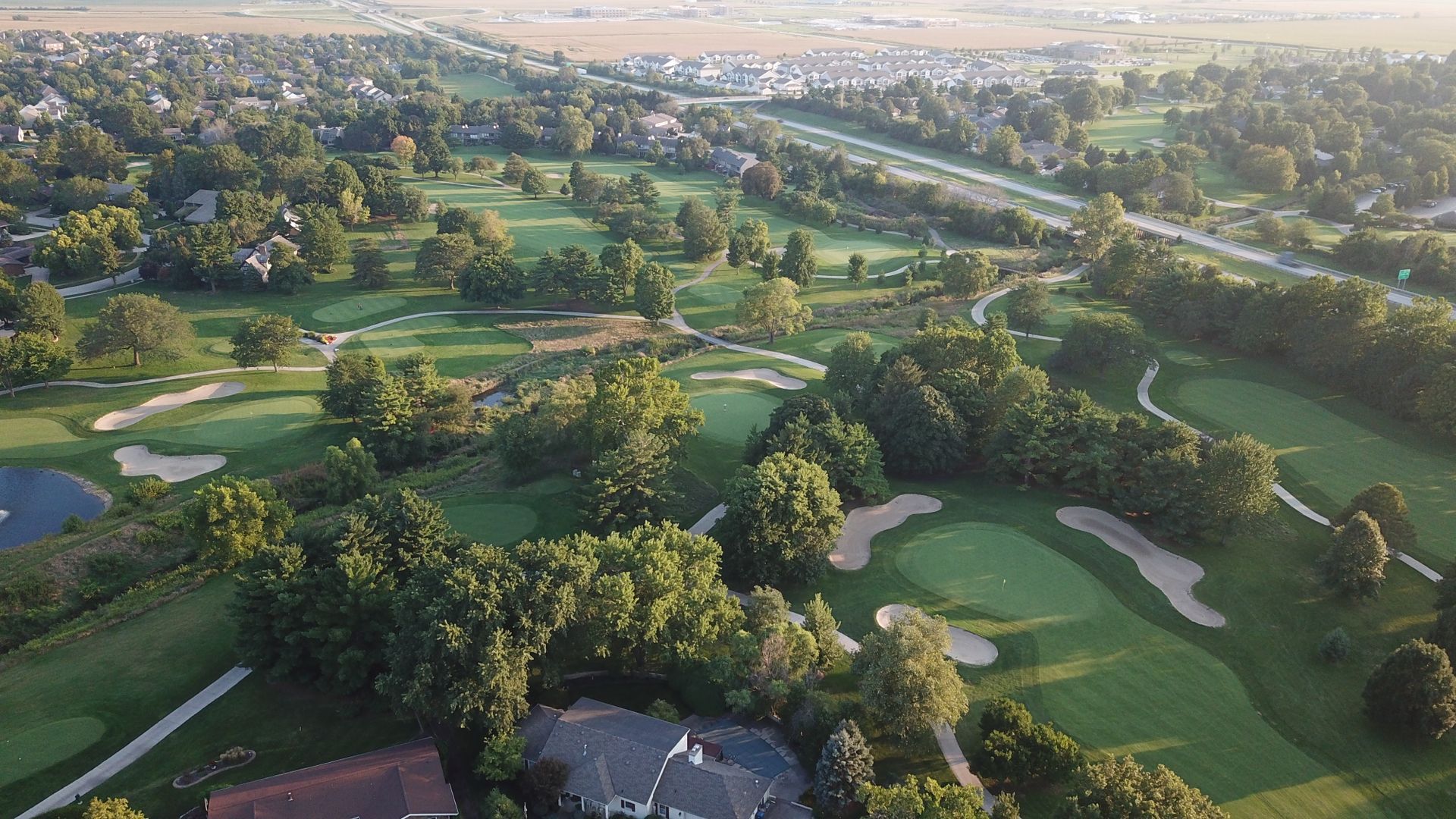 An aerial view of a golf course surrounded by trees and houses.